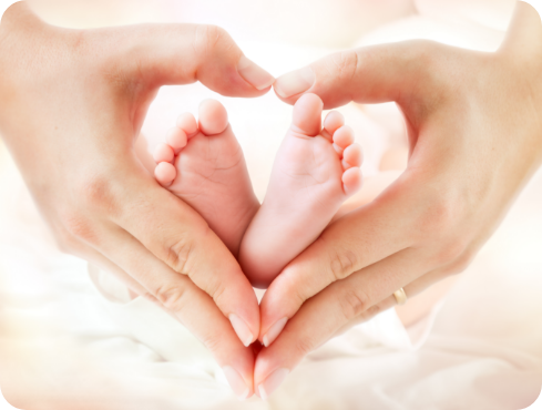 Mãe fazendo um coração com as mãos em volta dos pezinhos de um bebê